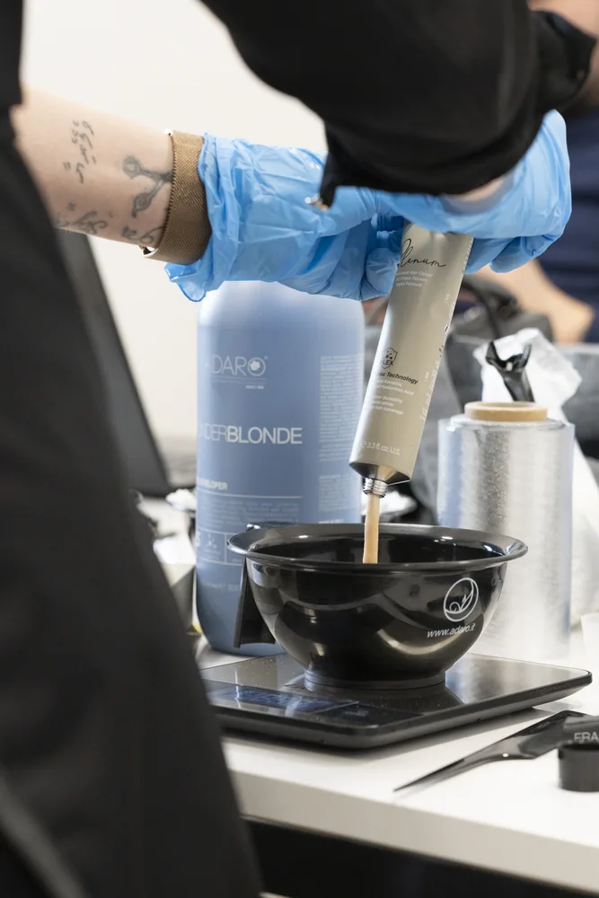 Stylist squeezing Plenum color into an Adaró bowl at a training class